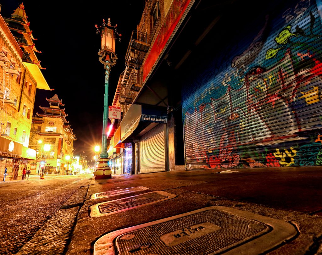 Nighttime photo of closed shop with graffitied door in San Francisco's Chinatown.